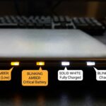 Close-up of laptop battery indicator light showing various colors